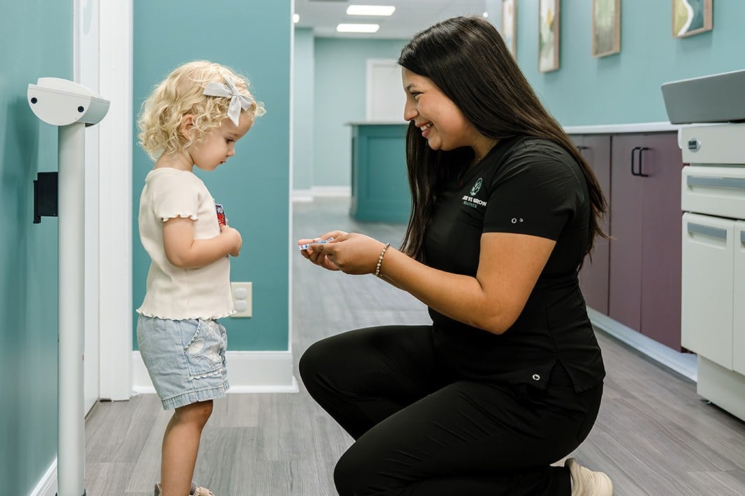 A Here We Grow team member weighing a toddler at a well child visit